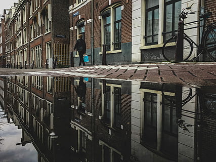 person walking on brick pavement, person in black suit walking reflection on body of water HD wallpaper