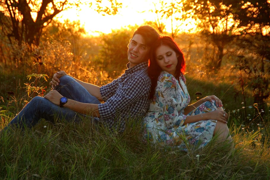 man and woman leaning to each other sitting on grass field during golden hour, HD wallpaper