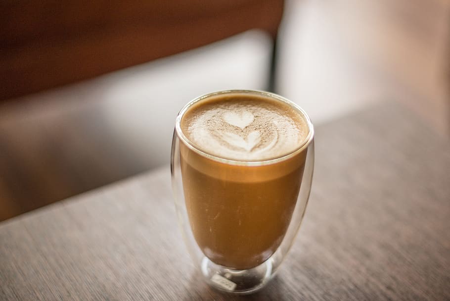 clear glass cup with espresso on top of a wooden table, flower