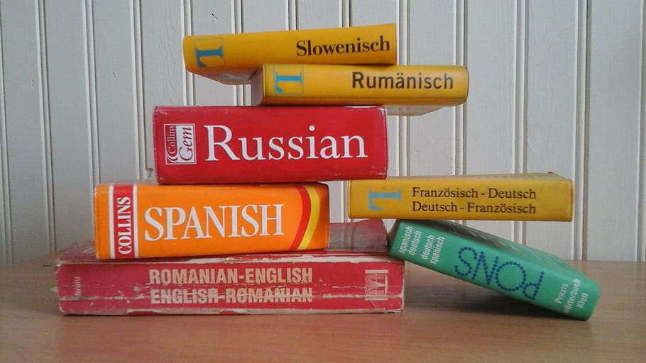assorted-titled book lot near white wall, Dictionary, Languages