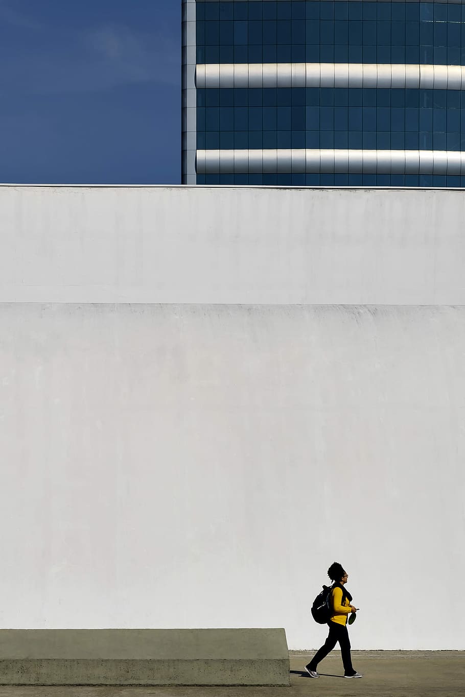 human in yellow long-sleeved T-shirt walking beside white concrete wall, man standing near on white wall paint, HD wallpaper