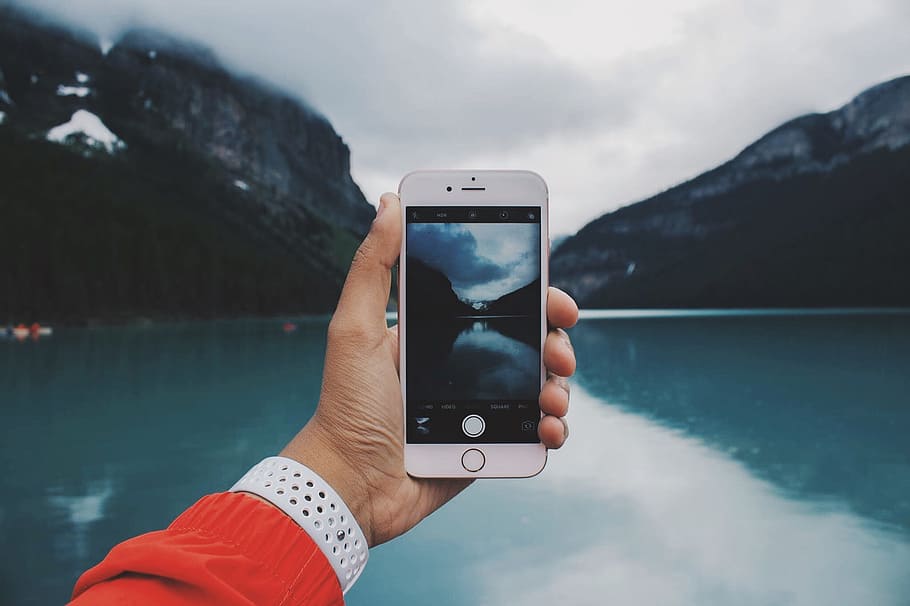 person taking photo of lake, silver iphone 6 taking picture of lake during cloudy day