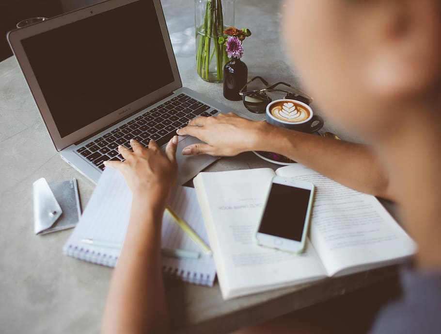 Writer at work, closeup photo of person holding laptop beside books and phone on table HD wallpaper