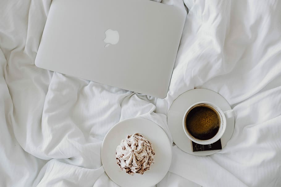Woman working on a laptop while enjoying a breakfast coffee and chocolate in bed, HD wallpaper