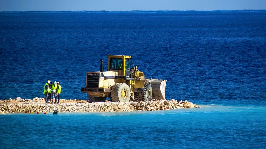 black and yellow skid-steer loader surrounded by body of water HD wallpaper