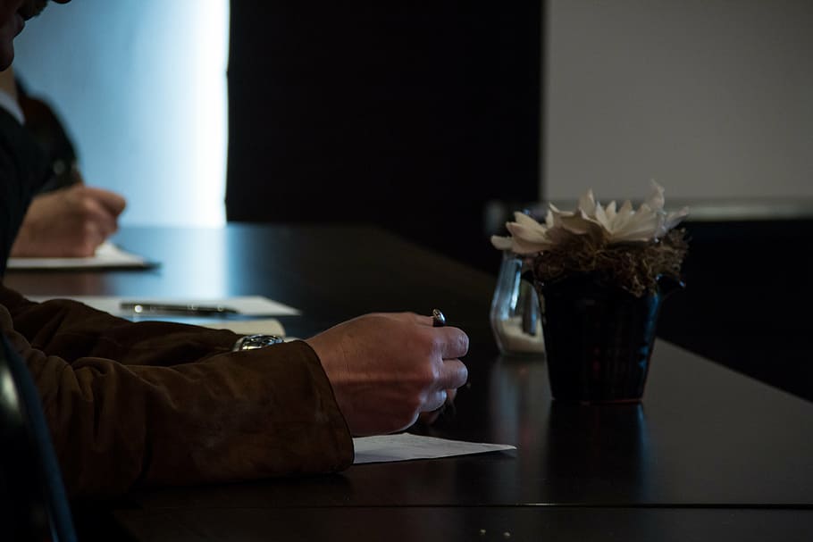 person holding pen near flower vase on black surface, note HD wallpaper