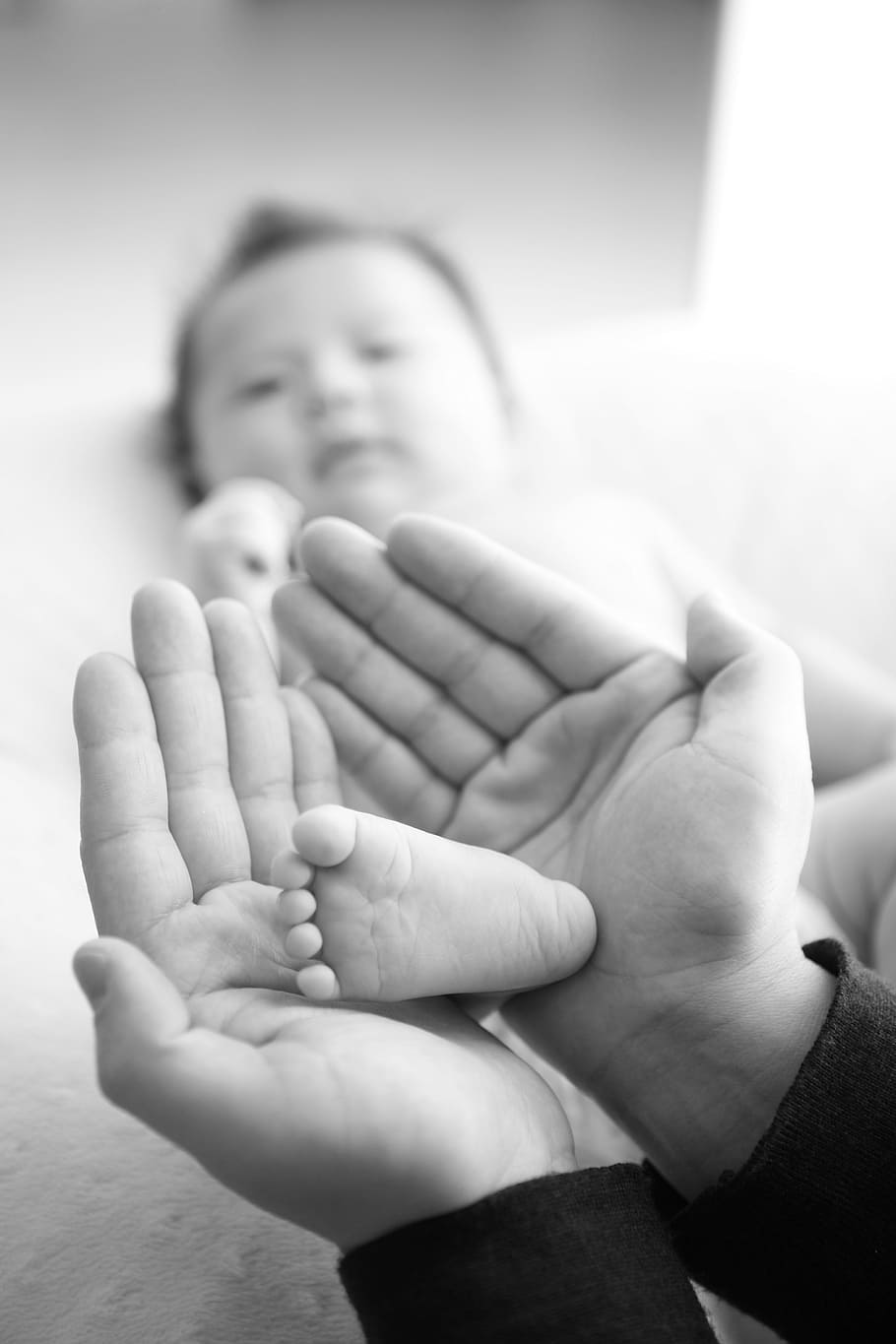 selective focus grayscale photography of baby's right foot on person's hands