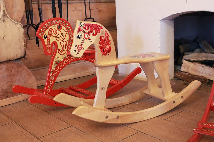 two red and tan rocking horses beside fireplace, horse-rocking chair