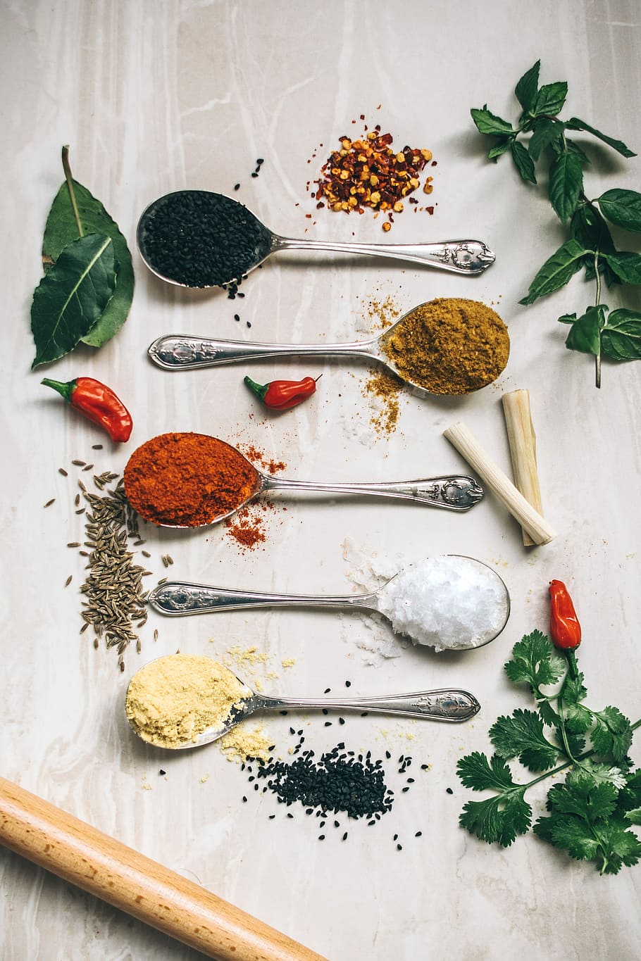 five gray spoons filled with assorted-color powders near chilli, flat lay photography of spoons filled with spice powders on furniture board