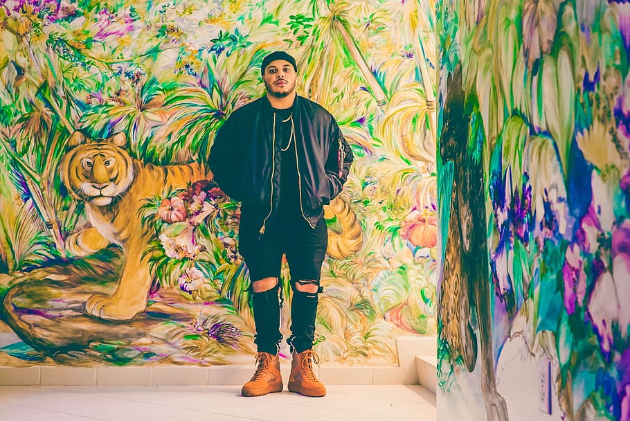 man standing behind assorted-design graffiti, man standing beside tiger painting at the wall HD wallpaper
