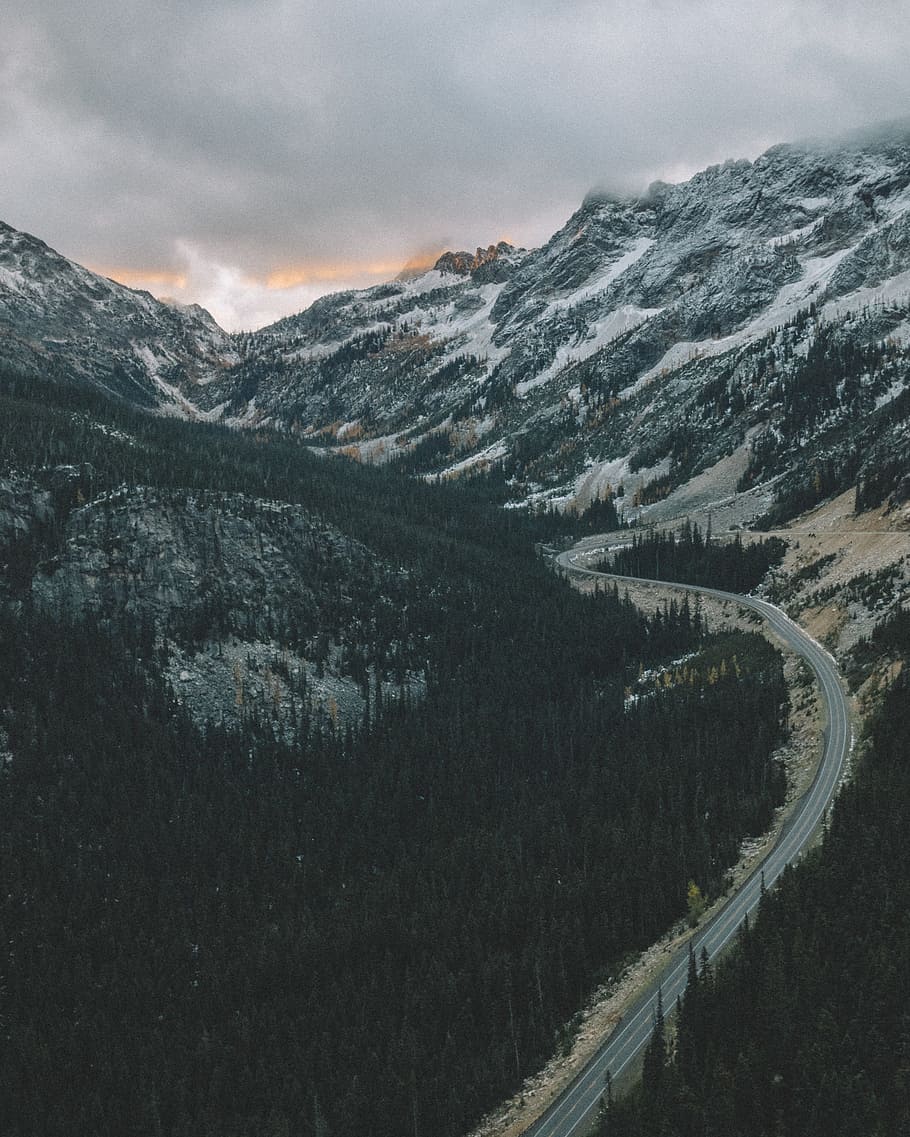 road between mountains under cloudy sky, road between trees background of mountain under cloudy sky HD wallpaper