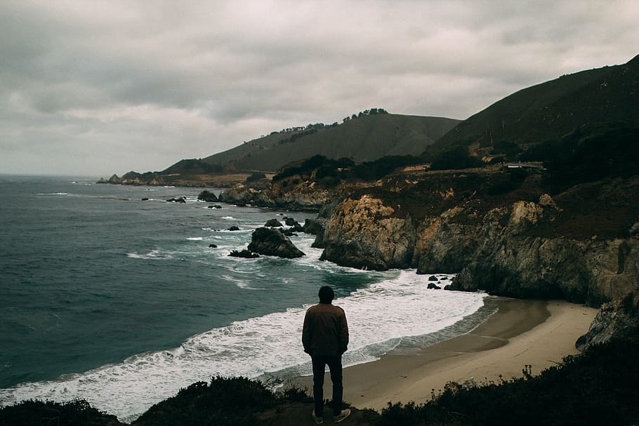 person standing on cliff near seashore during daytime, man HD wallpaper