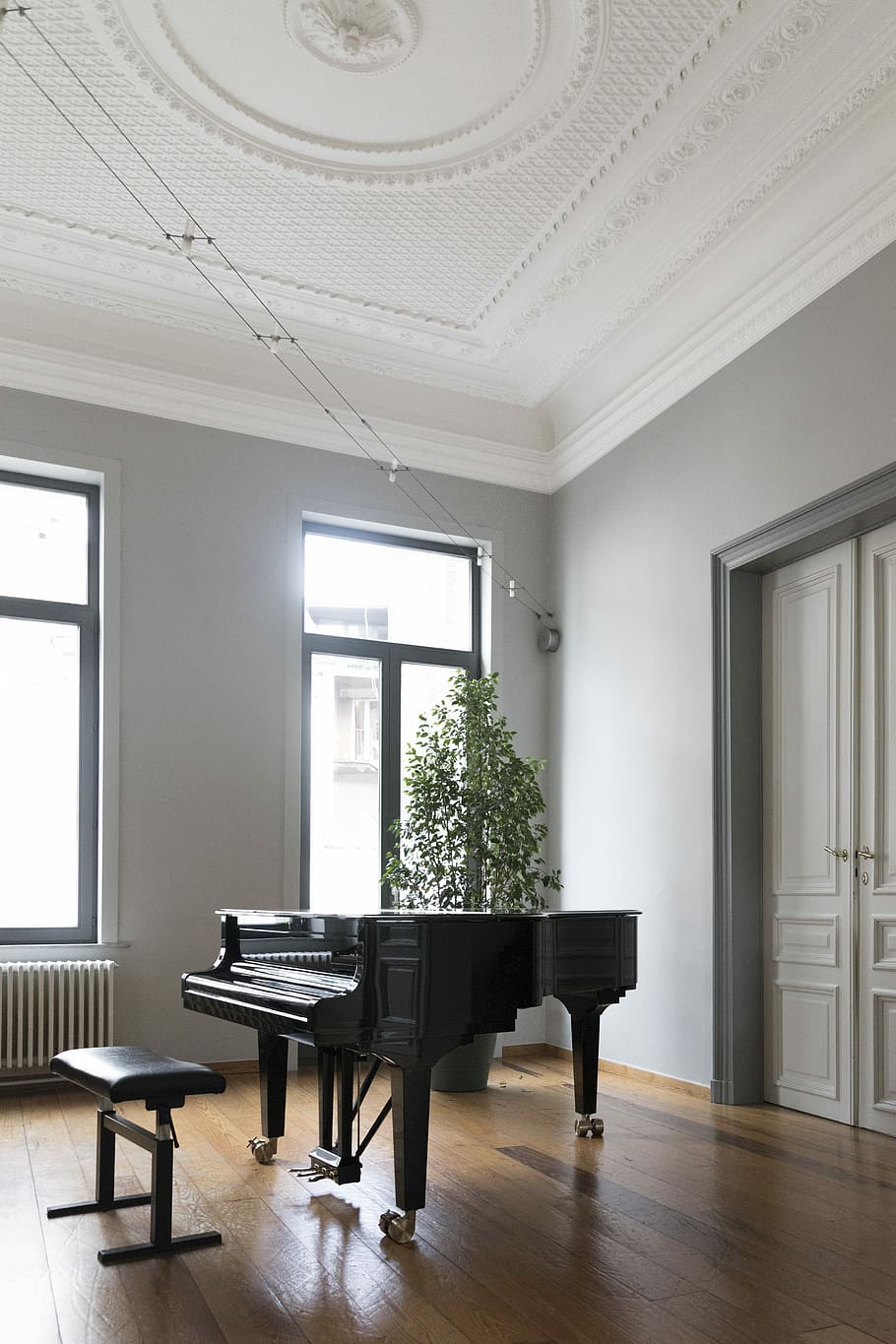 brown grand piano inside white room, black grand piano near window