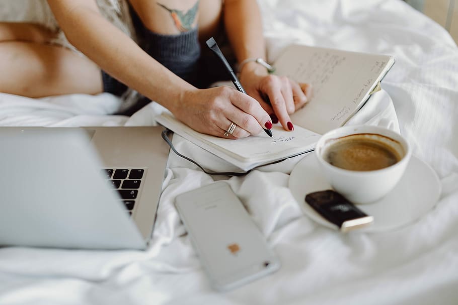 Woman working on a laptop while enjoying a breakfast coffee and chocolate in bed HD wallpaper