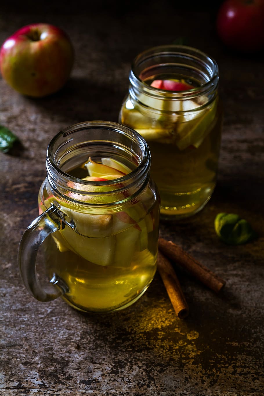 two drinking glasses filled with apple juice, two clear glass jars HD wallpaper