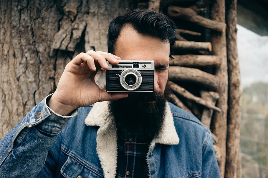 man in blue denim jacket holding camera, photographer, beard