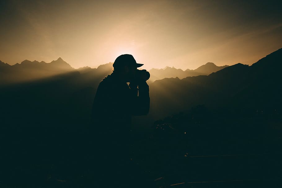 silhouette of man carrying camera near mountains during sunset, silhouette of man holding camera HD wallpaper