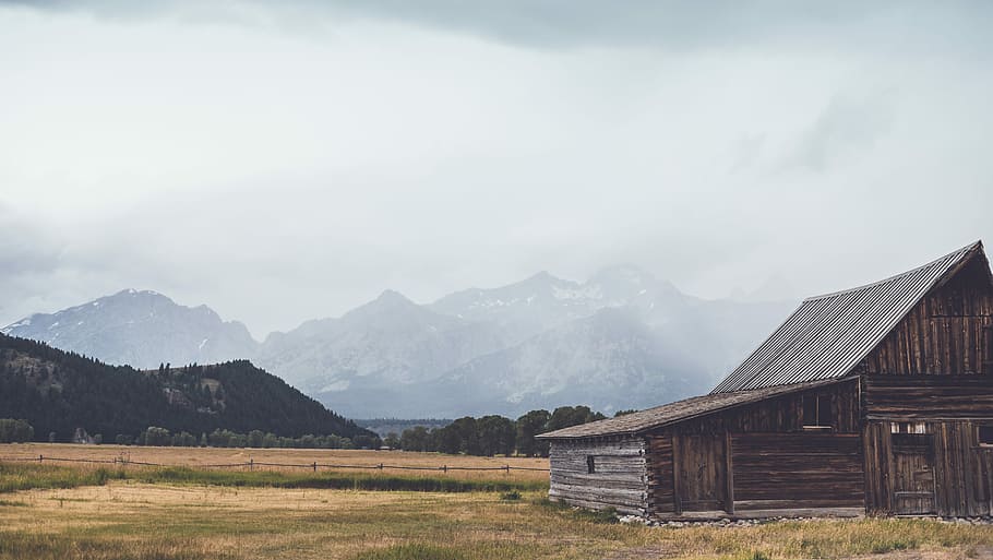 brown house and mountain, brown barn near mountains under cloudy skies HD wallpaper