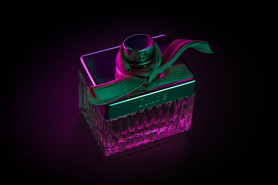 purple fragrance bottle, pink and green gift box with black background