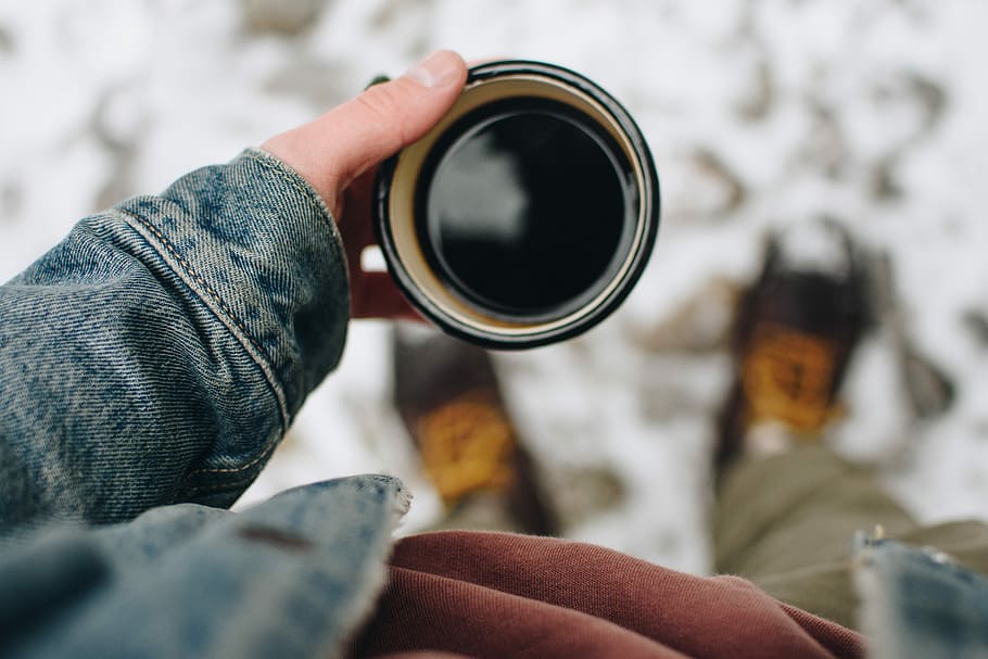 person holding mug, person standing on snow holding a cup of black coffee HD wallpaper