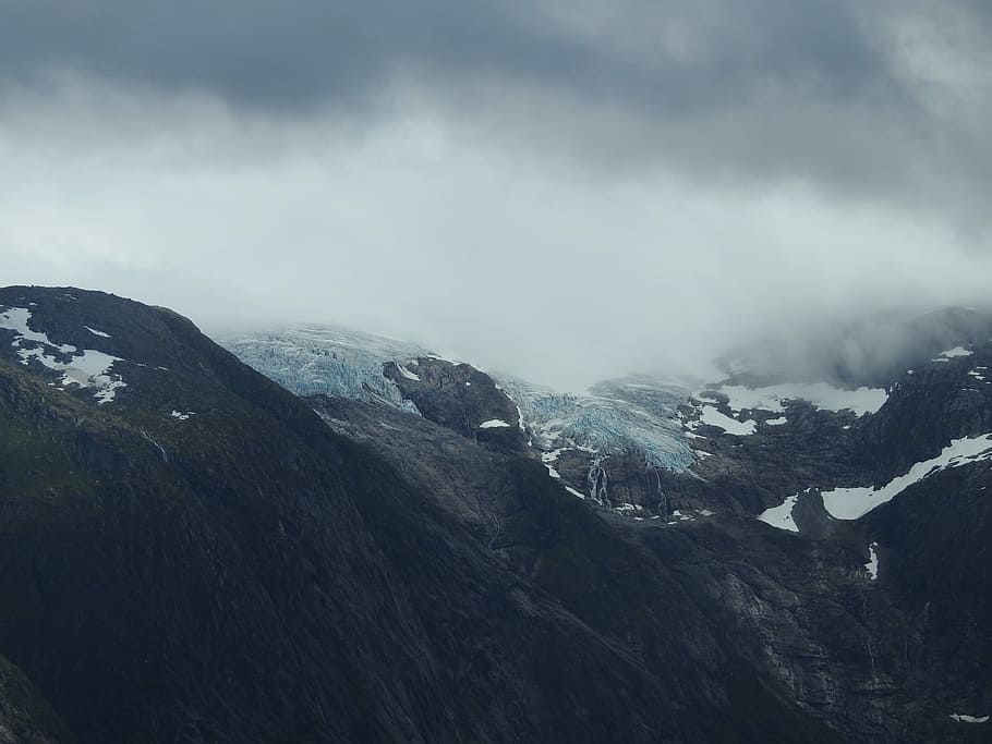 Lundebreen, a part of Norway’s biggest glacier., snow capped mountains under the gray clouds