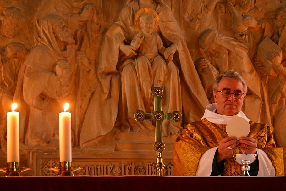 priest standing beside candles, communion, church, altar, cross