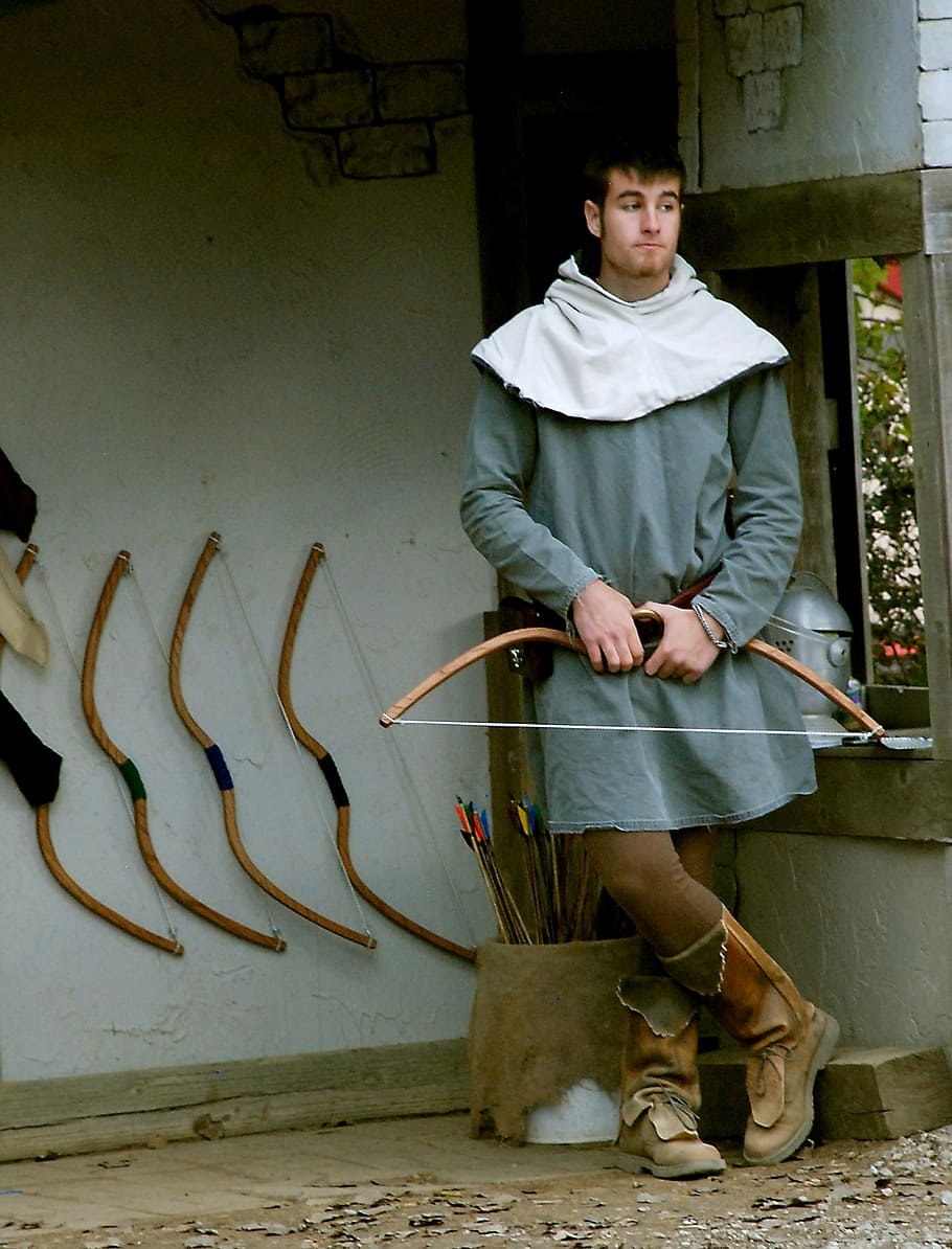 man holding bow standing near four racked bows, vendor, arrow HD wallpaper
