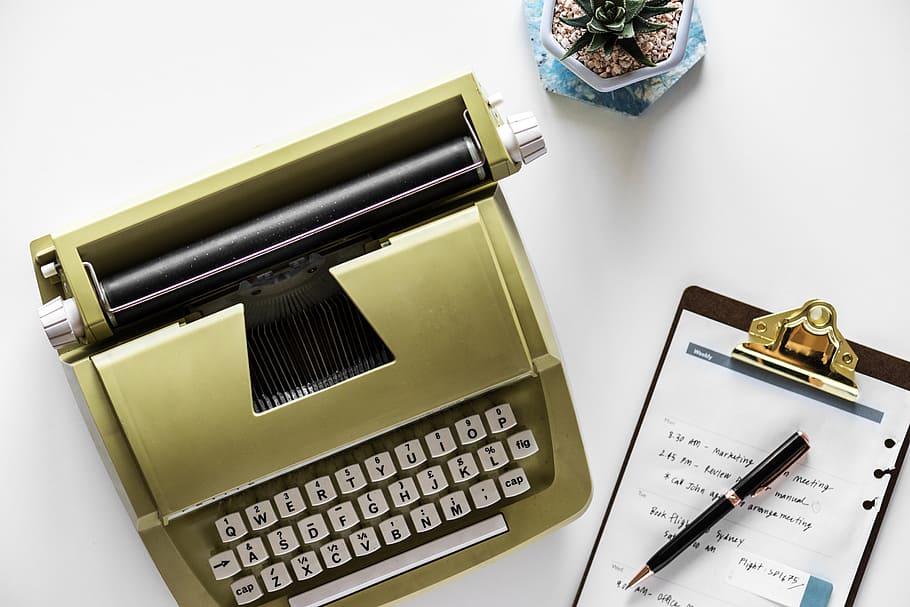 brown typewriter beside clipboard on white surface, office, business