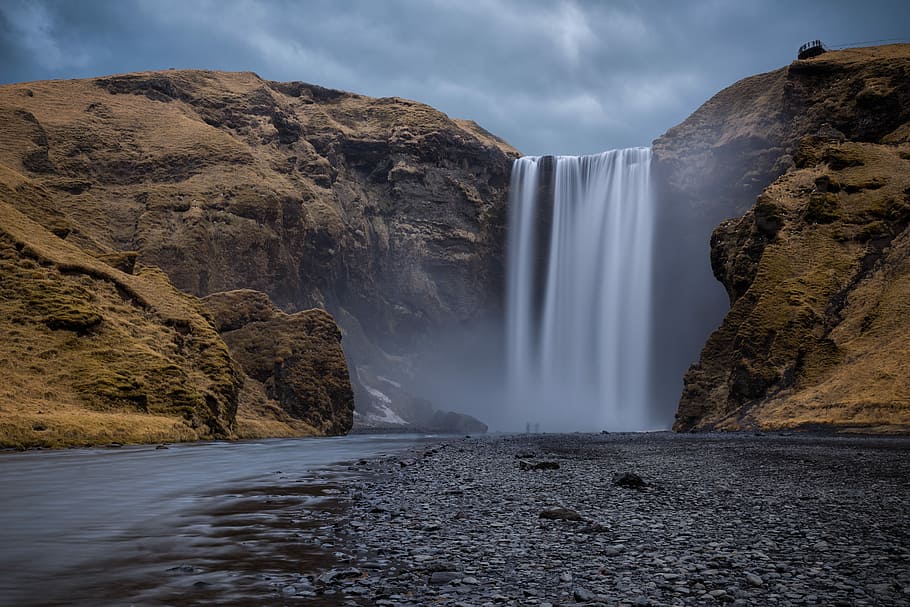 Skogafoss falls time lapse photography, waterfall pouring in a brown land formation HD wallpaper