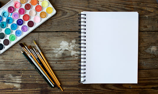 white sketch pad with coloring supplies on brown wooden desk HD wallpaper