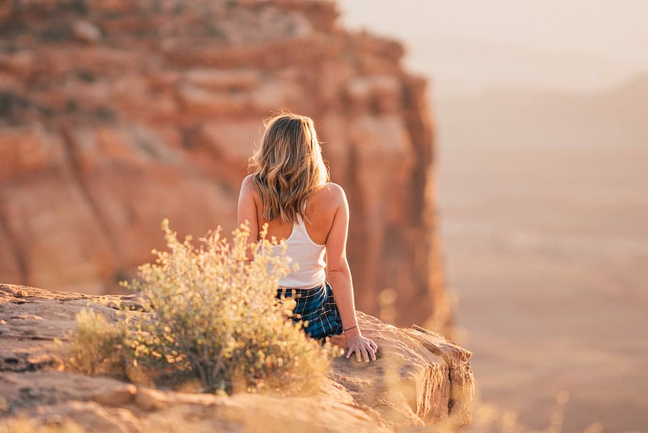 woman sitting on cliff during daytime, woman sitting on cliff near grass at daytime HD wallpaper