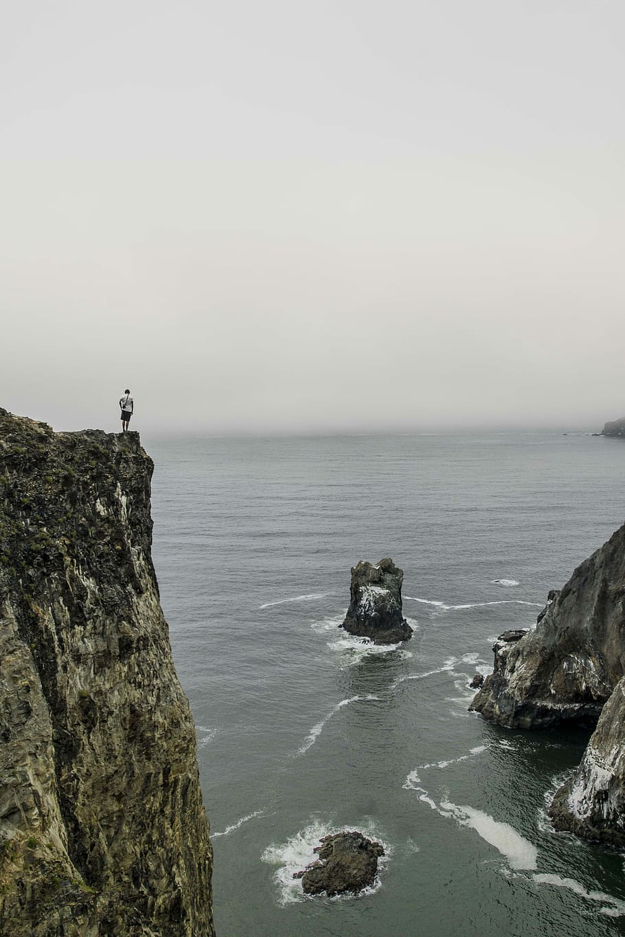 man standing on cliff under grey sky, rock, sea, ocean, water HD wallpaper