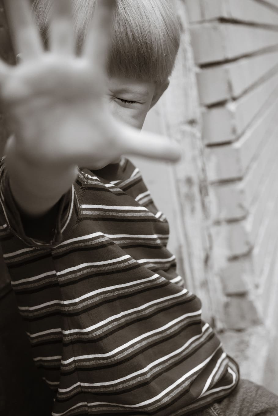 boy covering his face with hand in grayscale photography, child