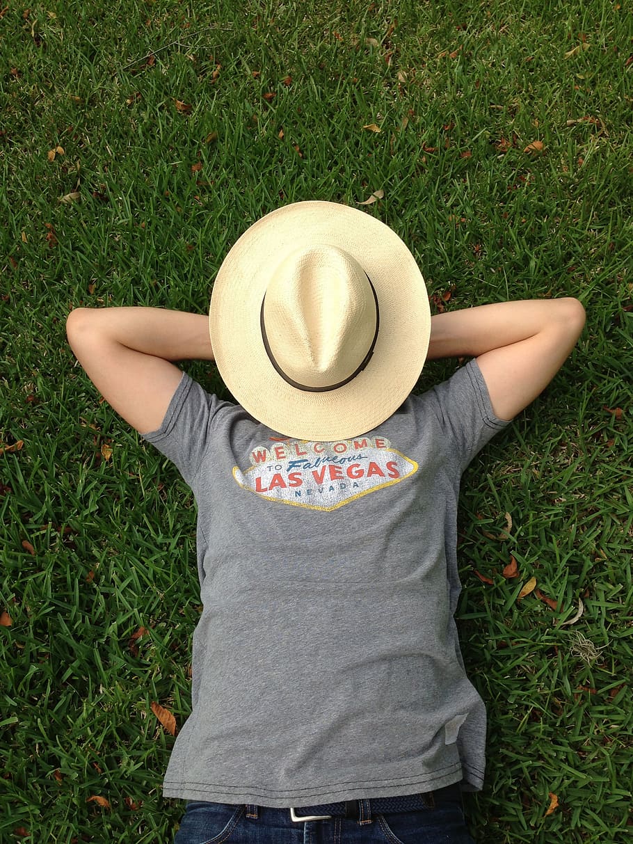 person in gray shirt lying on grass field with brown sun hat on face HD wallpaper