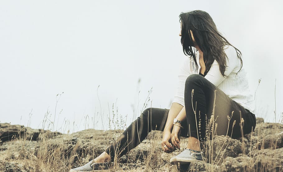 selective focus photography of woman in white long-sleeved shirt sitting on gray rock, woman sitting on rocks HD wallpaper