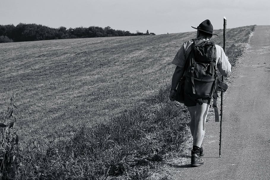 grayscale photo of man in hiking set walking along the pathway HD wallpaper