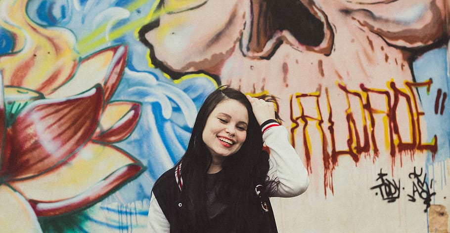 woman wearing black and white letterman jacket standing in front of mural painting, woman, varsity jacket, standing, wall, graffiti, piercing HD wallpaper