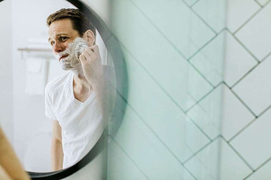 man shaving in front of mirror, man shaving beard in front of mirror