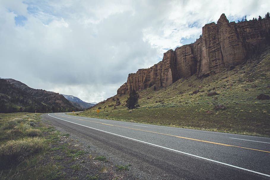 cliff near road during daytime, asphalt, bushes, clouds, daylight HD wallpaper