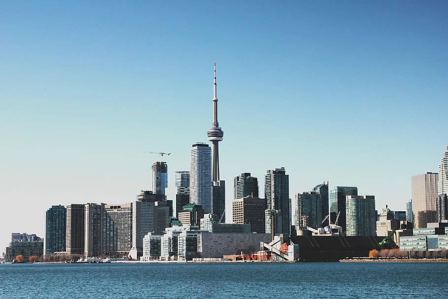 photo of high-rise buildings near body of calm water during daytime, city buildings near body of water HD wallpaper