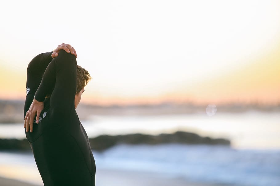 depth of field photography of person in black wetsuit standing in front of shore, man looking in the ocean HD wallpaper