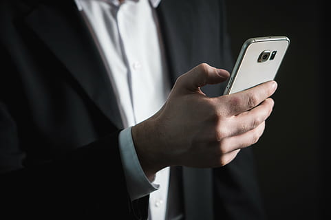 person in black formal coat holding Samsung Galaxy Android smarpthone HD wallpaper