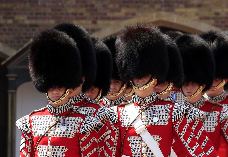 men wearing red uniforms and black hats, royal guard, buckingham palace