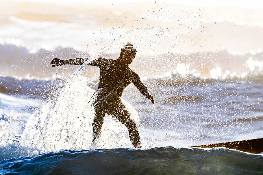 silhouette photography of man surfing on body of water, man riding surfboard on body of water HD wallpaper