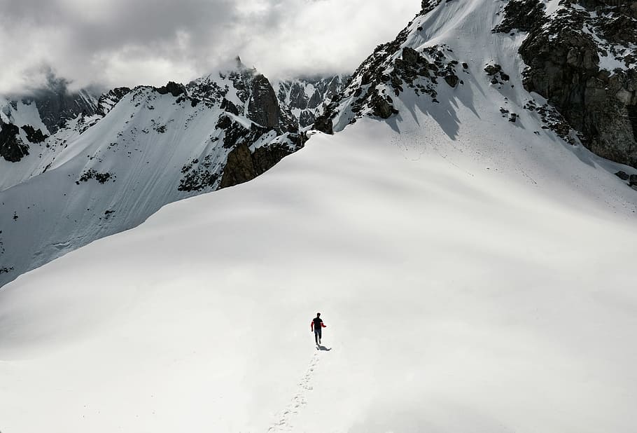 man climbing snow-covered mountain, person walking on snow covered mountain