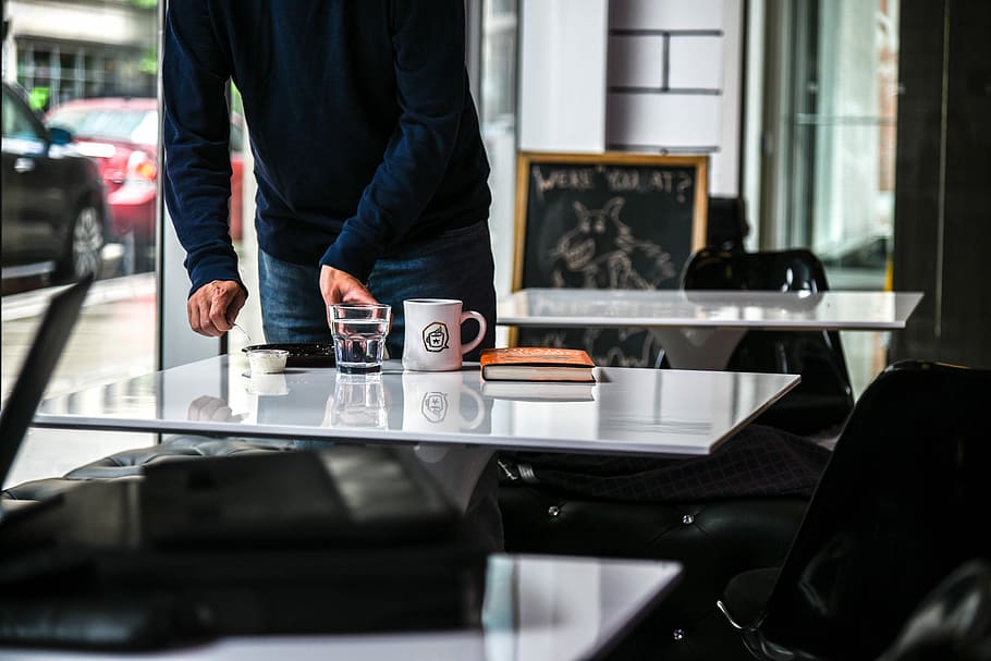 standing person holding glass of water on beside table, person standing beside glass table with mug HD wallpaper
