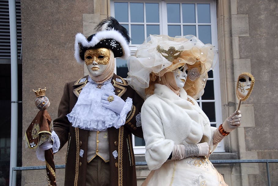 man and woman wearing masquerade with Royal costume standing neat window during daytime