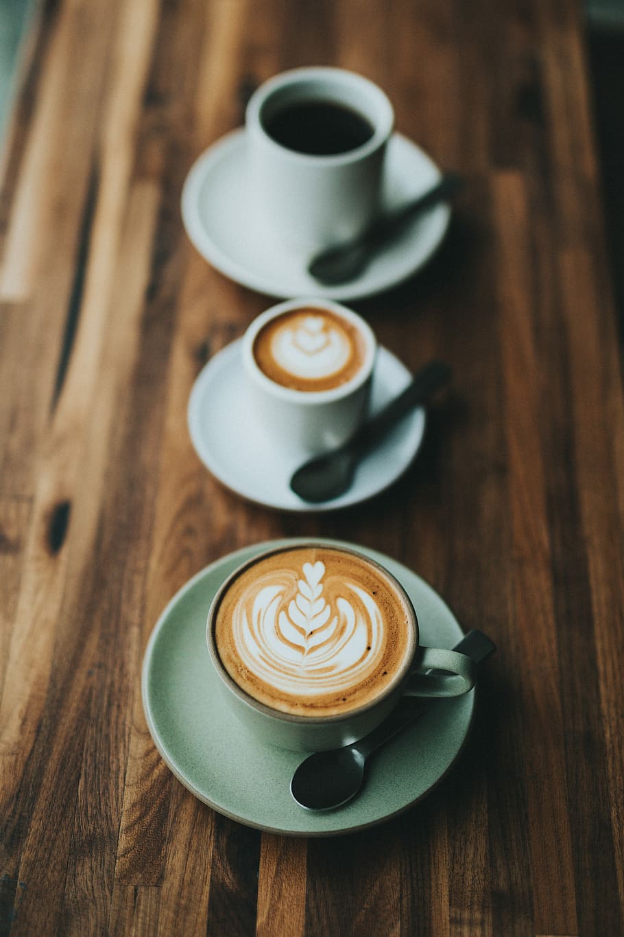 white coffee cup on saucer with teaspoon filled with coffee and frothed milk, three ceramic mugs with latte HD wallpaper