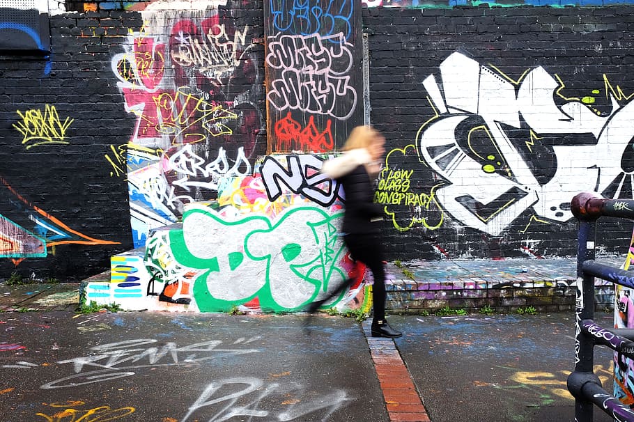panning photography of woman walking beside wall with graffiti art, woman walking beside wall HD wallpaper
