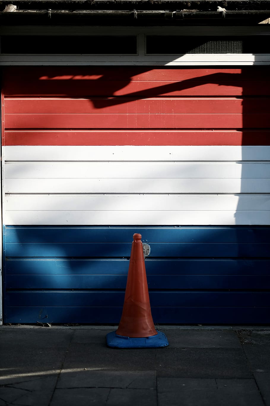 red, white , and blue wooden garage door, red and blue traffic cone